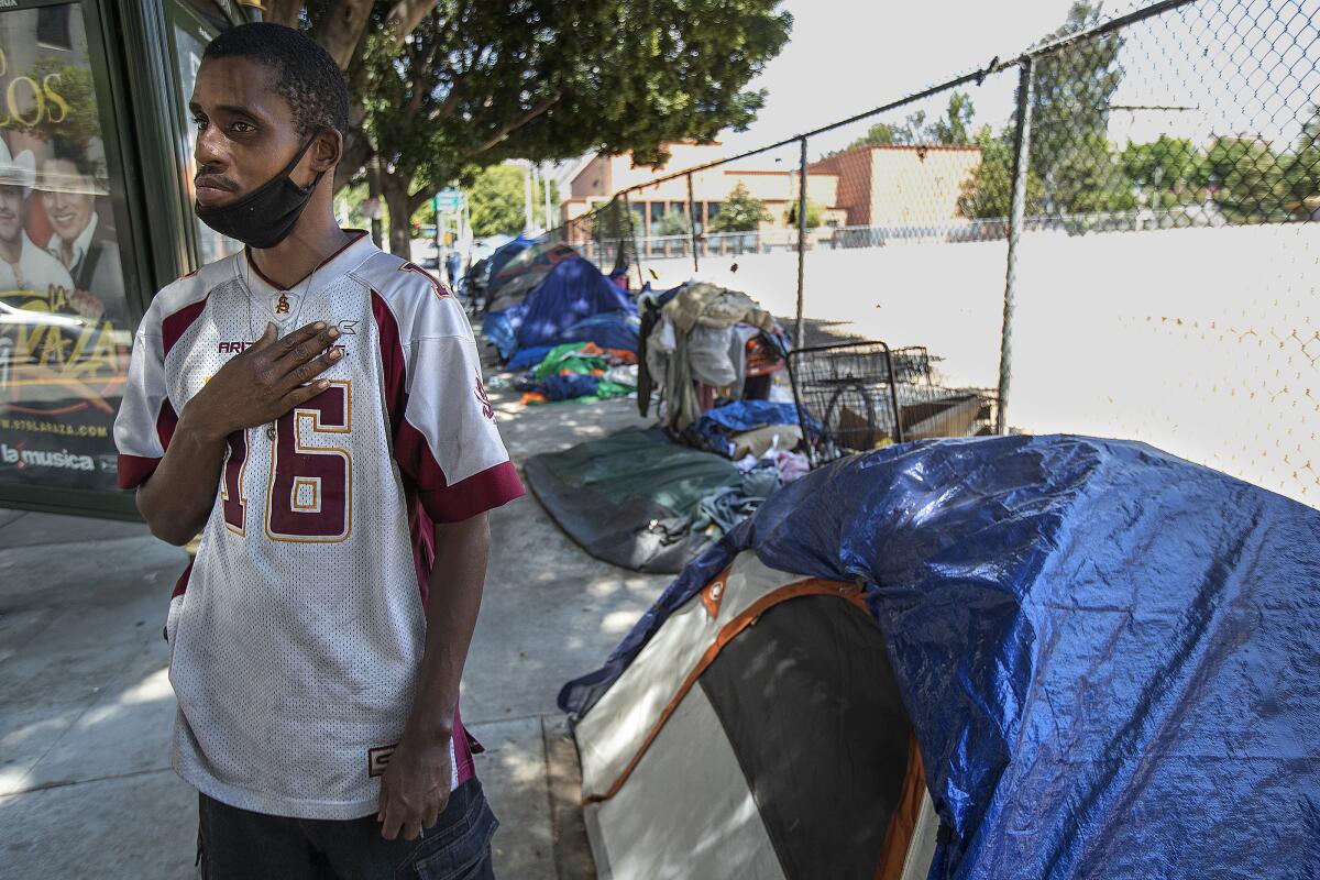 A man is photographed outside his tent at a homeless encampment in Los Angeles 