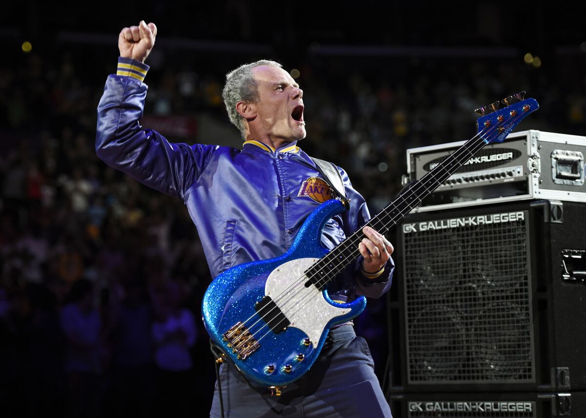 FILE - In this April 13, 2014 file photo, Flea, bassist for the Red Hot Chili Peppers, plays the national anthem prior to an NBA basketball game between the Los Angeles Lakers and the Memphis Grizzlies in Los Angeles. Flea turned 59 on Saturday, Oct. 16, 2021, and his Silverlake Conservatory of Music turned 20, and they celebrated with a joint party in the parking lot for the Los Angeles school that often serves as a de facto performance space for its faculty and students. (AP Photo/Mark J. Terrill, File)