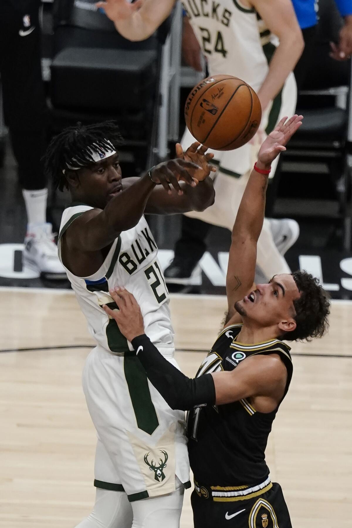 The Bucks' Jrue Holiday passes while being defended by the Hawks' Trae Young in Game 6 on July 3, 2021.