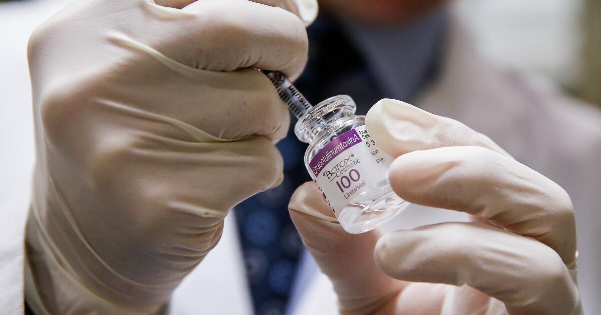 Doctor draws Botox into a syringe before administering it to a patient