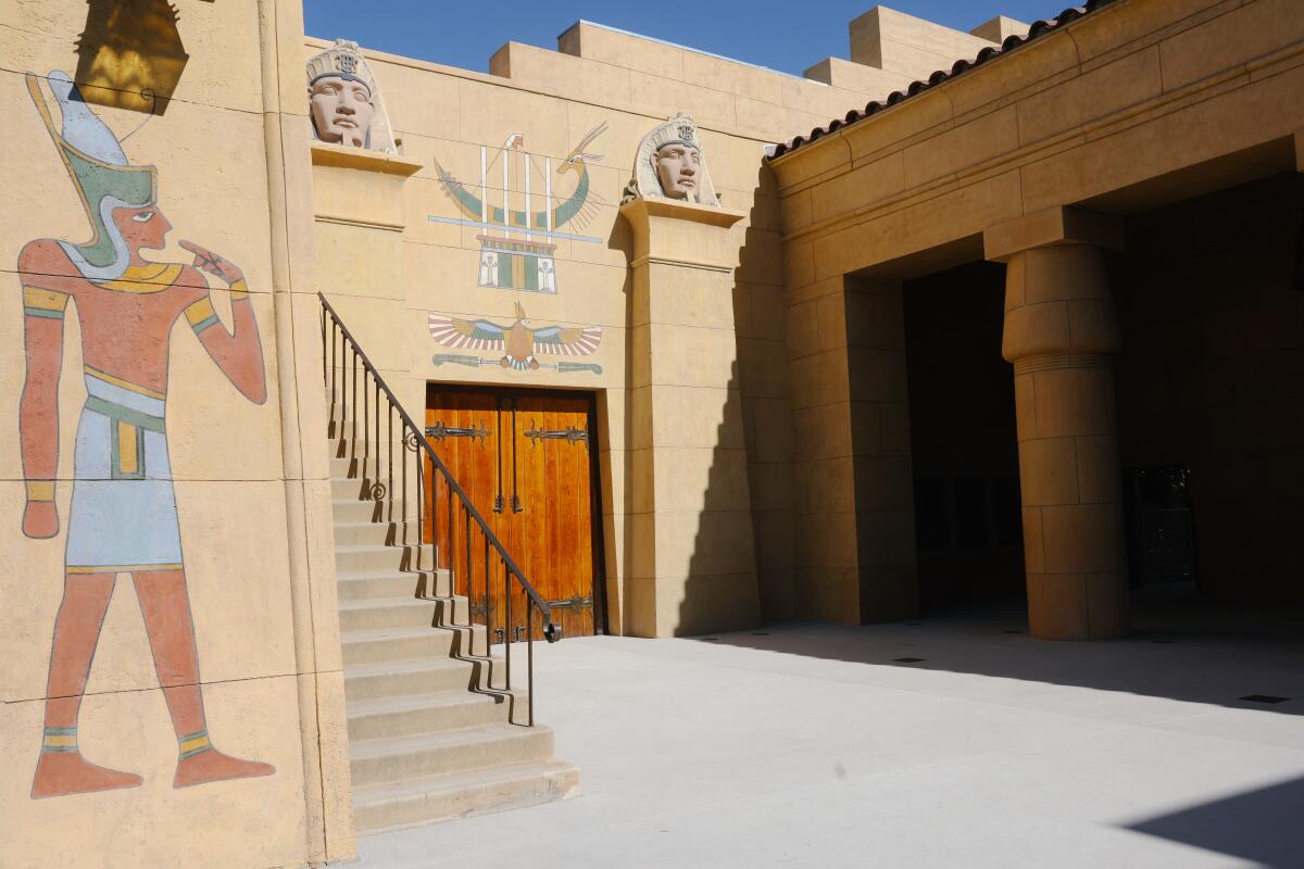A building inspired by ancient Egyptian architecture features painted figures on the walls and a sunny courtyard.
