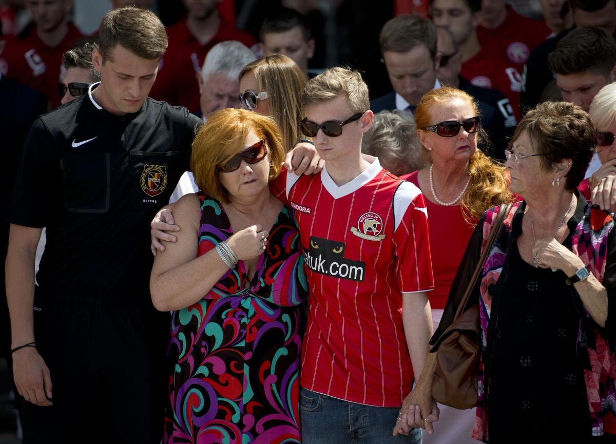 Owen Richards, center, who lost a brother, uncle and grandfather in the Tunisia attacks, observes a minute's silence with his mother Suzy Evans, second from the left, outside Walsall Football Club in central England.