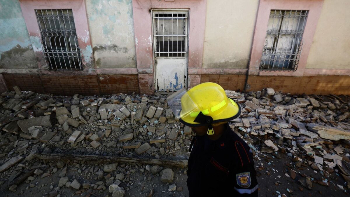 A firefighter walks in front of a house in Valencia, Venezuela, that was damaged during an earthquake on Dec. 27.