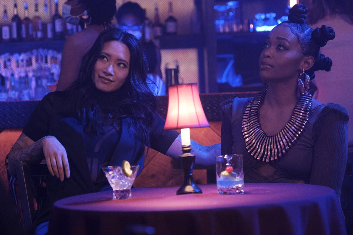 Two women sit at a bar table.