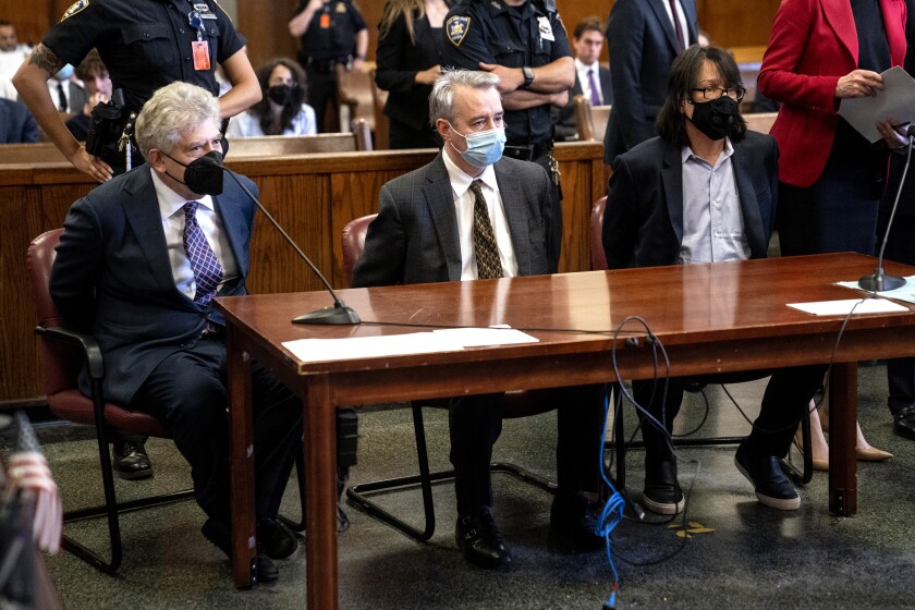 Three defendants sit behind a table in a criminal court.