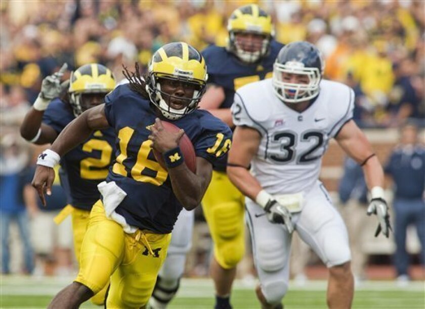 Michigan quarterback Denard Robinson (16) rushes past Connecticut linebacker Scott Lutrus (32) in the first quarter of an NCAA college football game, Saturday, Sept. 4, 2010, in Ann Arbor, Mich. (AP Photo/Tony Ding)