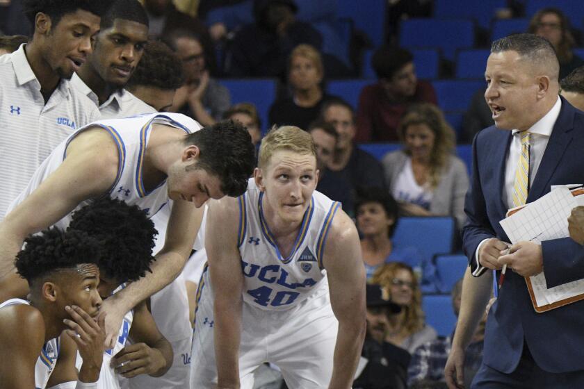 UCLA assistant coach David Grace talks to players during a timeout 