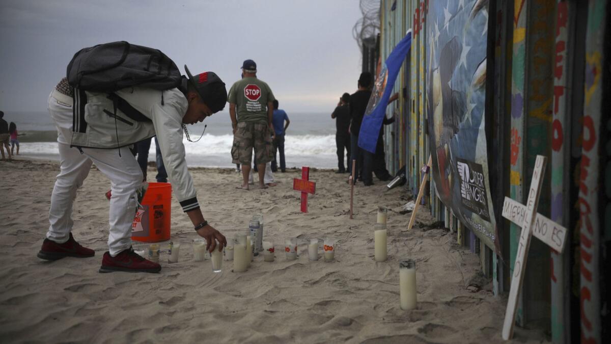 Candles are placed Saturday on the Tijuana side of the U.S.-Mexico border fence in memory of migrants who have died during their journey toward the U.S.