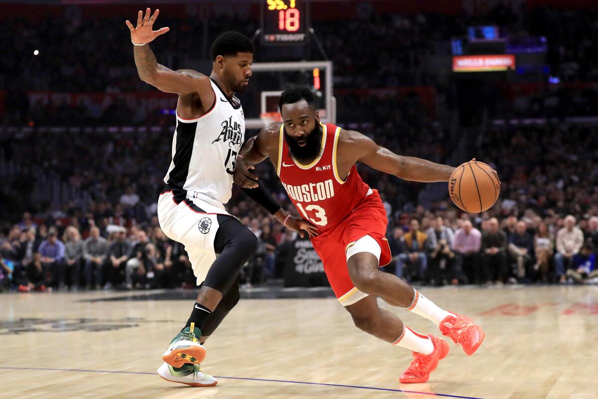 Clippers forward Paul George tries to cut off a drive by Rockets guard James Harden during their game Nov. 22, 2019, at Staples Center.