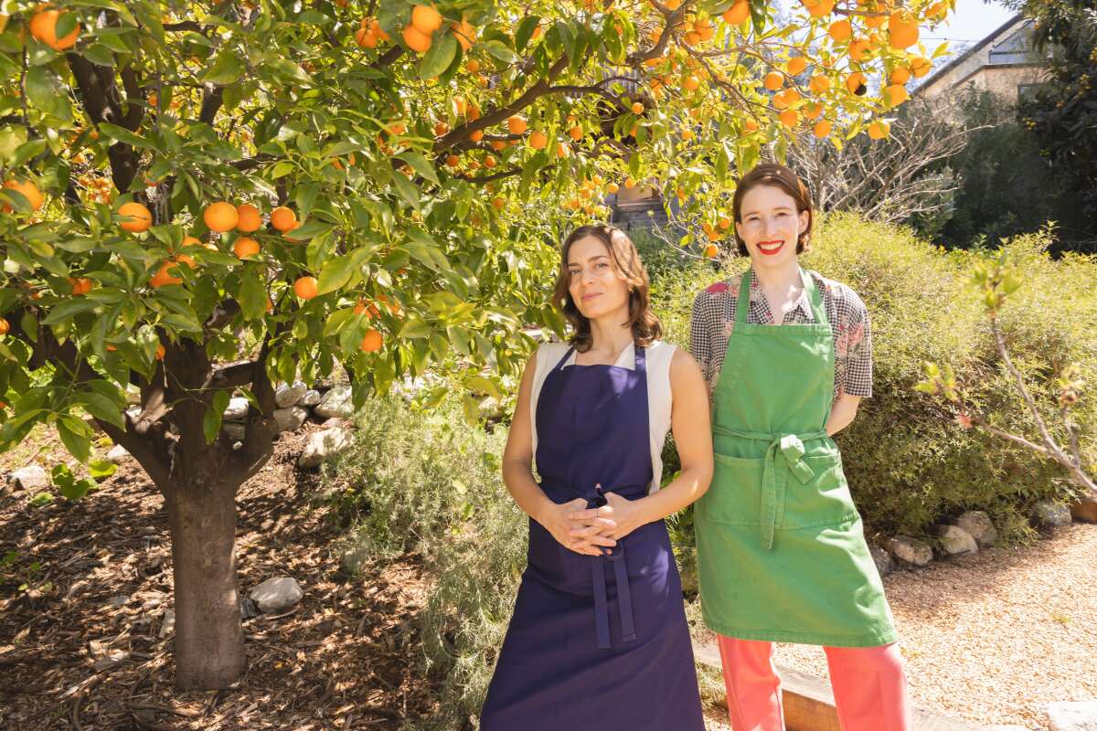 Kismet chef-owners Sara Kramer and Sarah Hymanson stand under an orange tree.