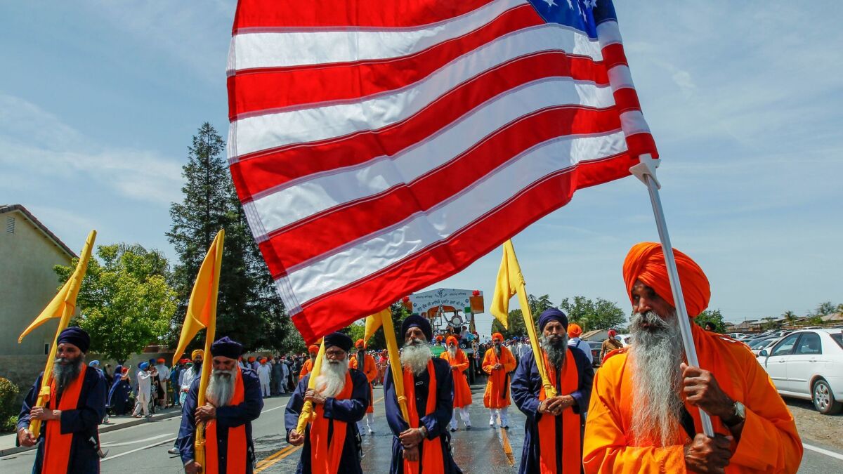 Sikh holy men walk in front of a procession carrying their holy book, Guru Granth Sahib, during a Nagar Kirtan parade. (Irfan Khan / Los Angeles Times)