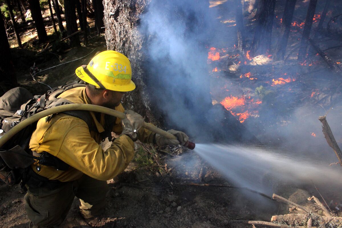 A firefighter sprays flames on the northwest flank of the August Complex fire in Trinity County on Sept. 22