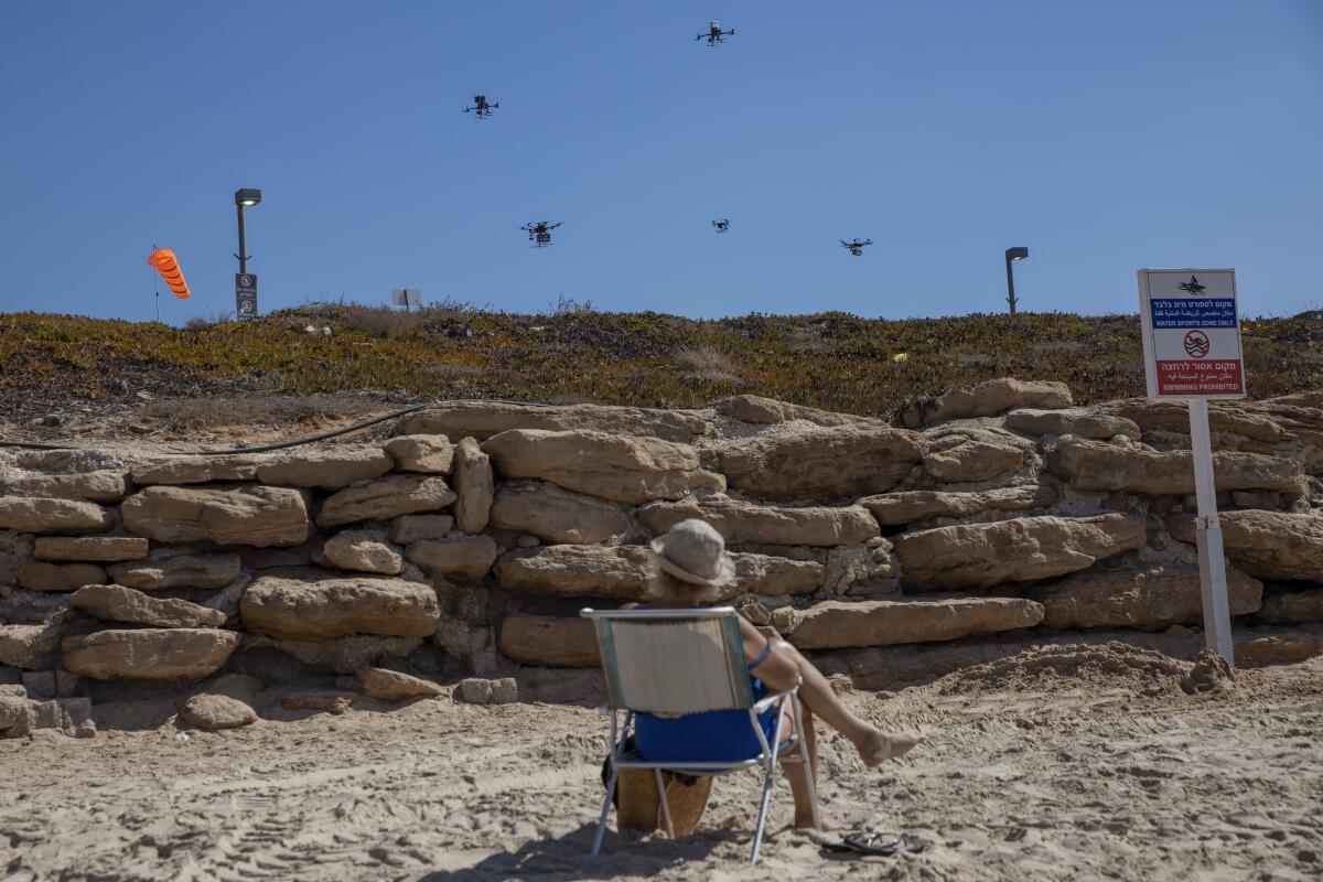 A woman looks at drones carrying goods