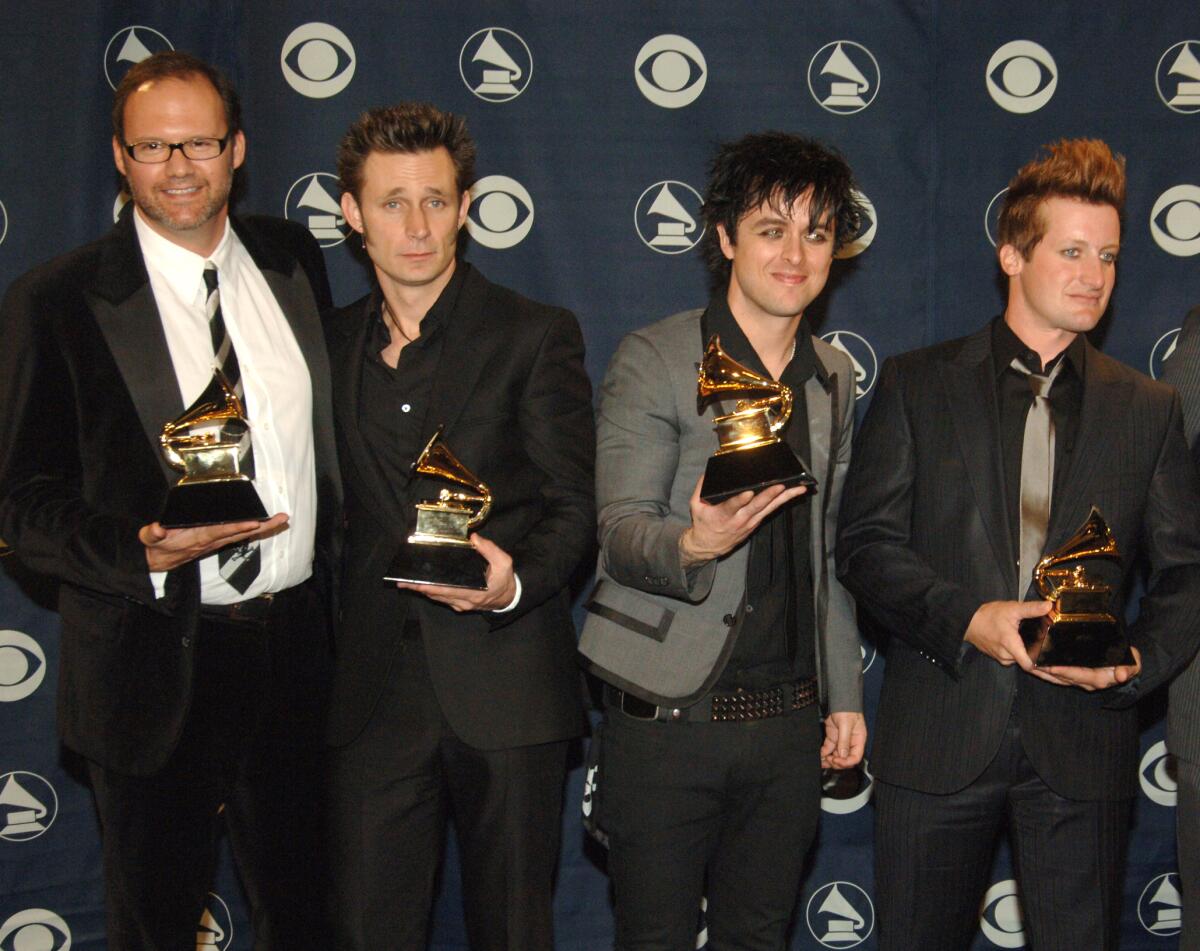 Four men hold Grammy awards.