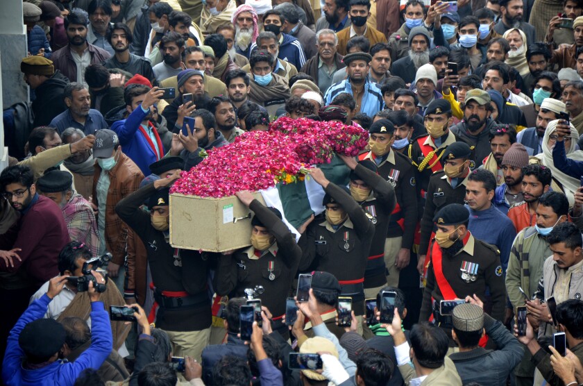 Army soldiers carry a national flag-wrapped casket of an army officer who was killed during a gunbattle with militants in an area of country's volatile southwestern Baluchistan province, at a funeral prayer, in Faisalabad, Pakistan, Friday, Feb. 4, 2022. Twin attacks by separatists on Pakistani military posts in the the province triggered intense firefights that lasted hours and killed multiple soldiers and assailants, Pakistan's interior minister and the military said Thursday. (AP Photo/Abdul Majid)