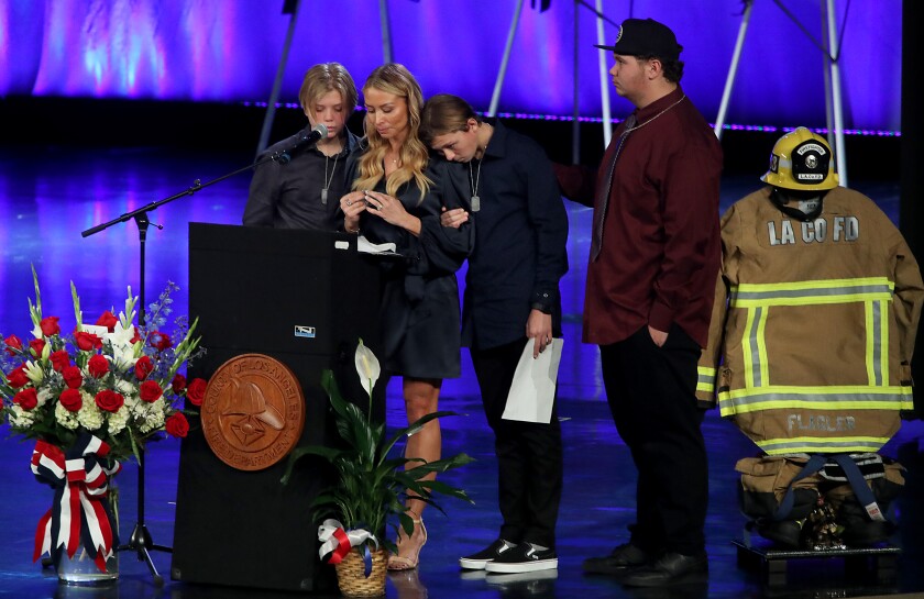 Four people stand behind or near a lectern.