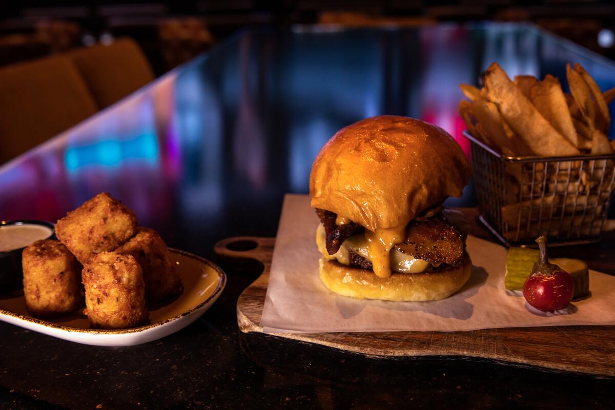 Stuffed tater tots, left, next to a burger dripping with cheese