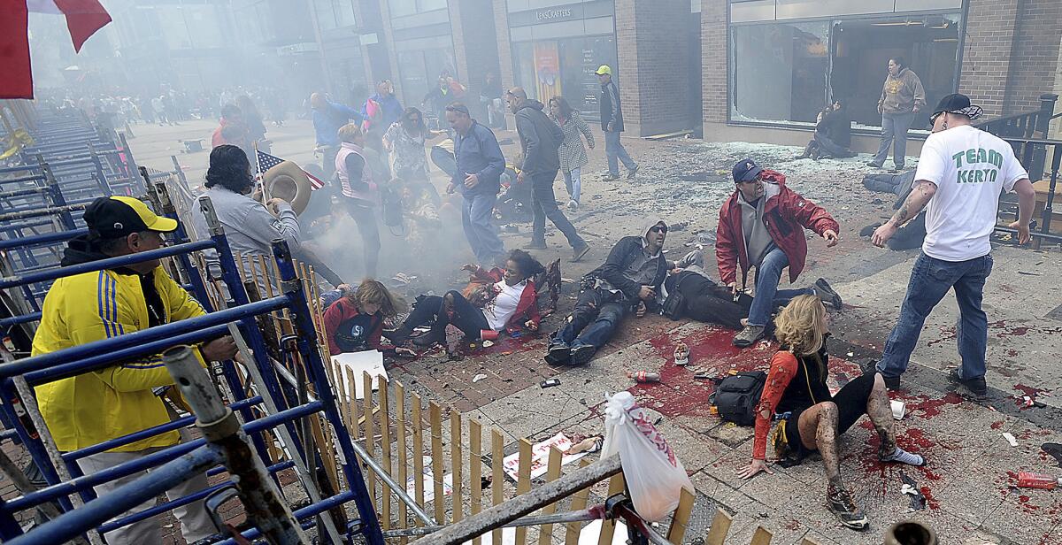 Injured people lie on the ground near the Boston Marathon finish line after an explosion Monday.