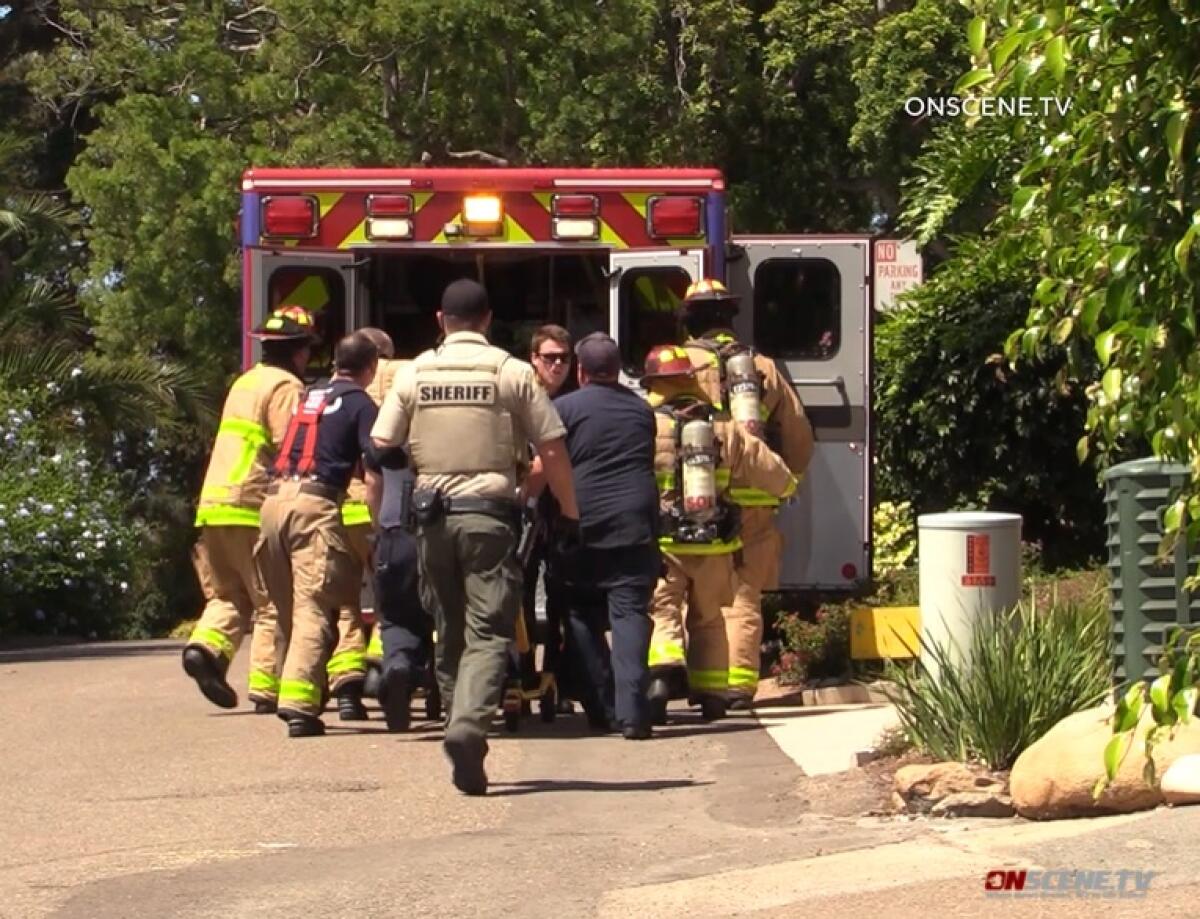 Del Mar crews roll an unresponsive man toward an ambulance Friday afternoon following a house fire on Luneta Drive.