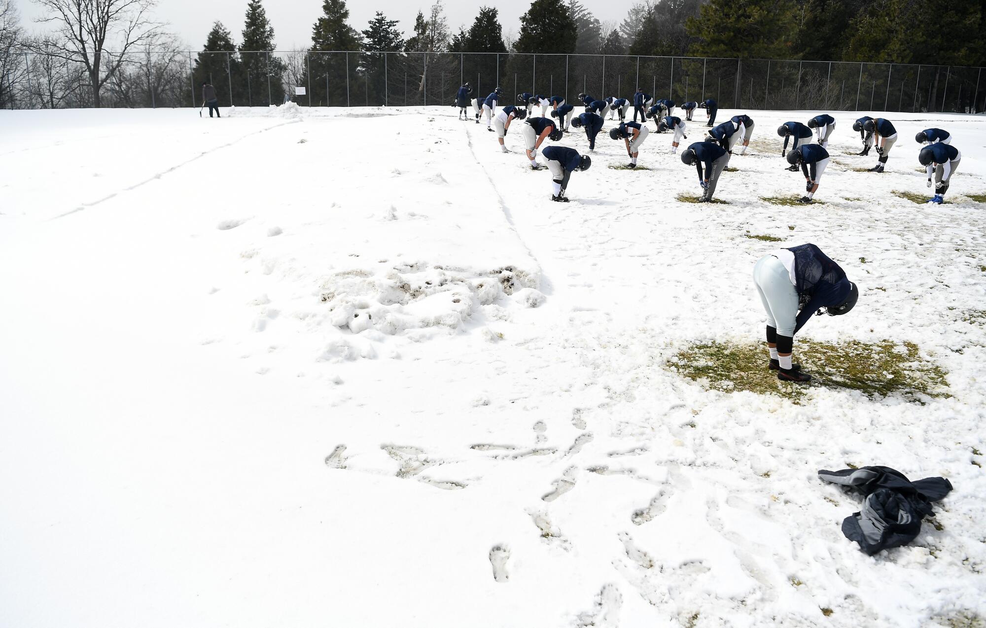 Rim of the World High School football players stretch on the practice field after a snowstorm.