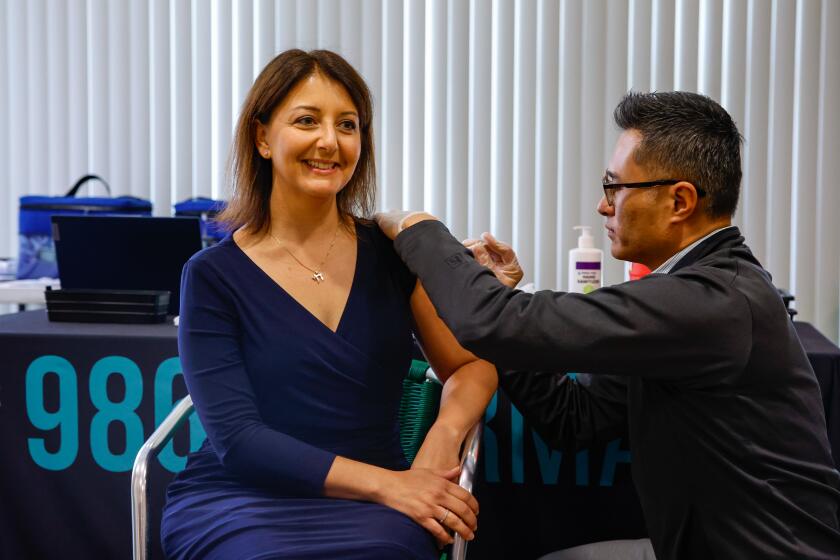 Los Angeles, CA - October 11: CDC Director Dr. Mandy Cohen gets a covid vaccination at an event at Stovall Terrace Apartments a senior community on Wednesday, Oct. 11, 2023 Dr. Ken Thai, pharmacist, CEO and Board of Director of 986 Pharmacy gives Cohen her covid shot. (Jason Armond / Los Angeles Times)