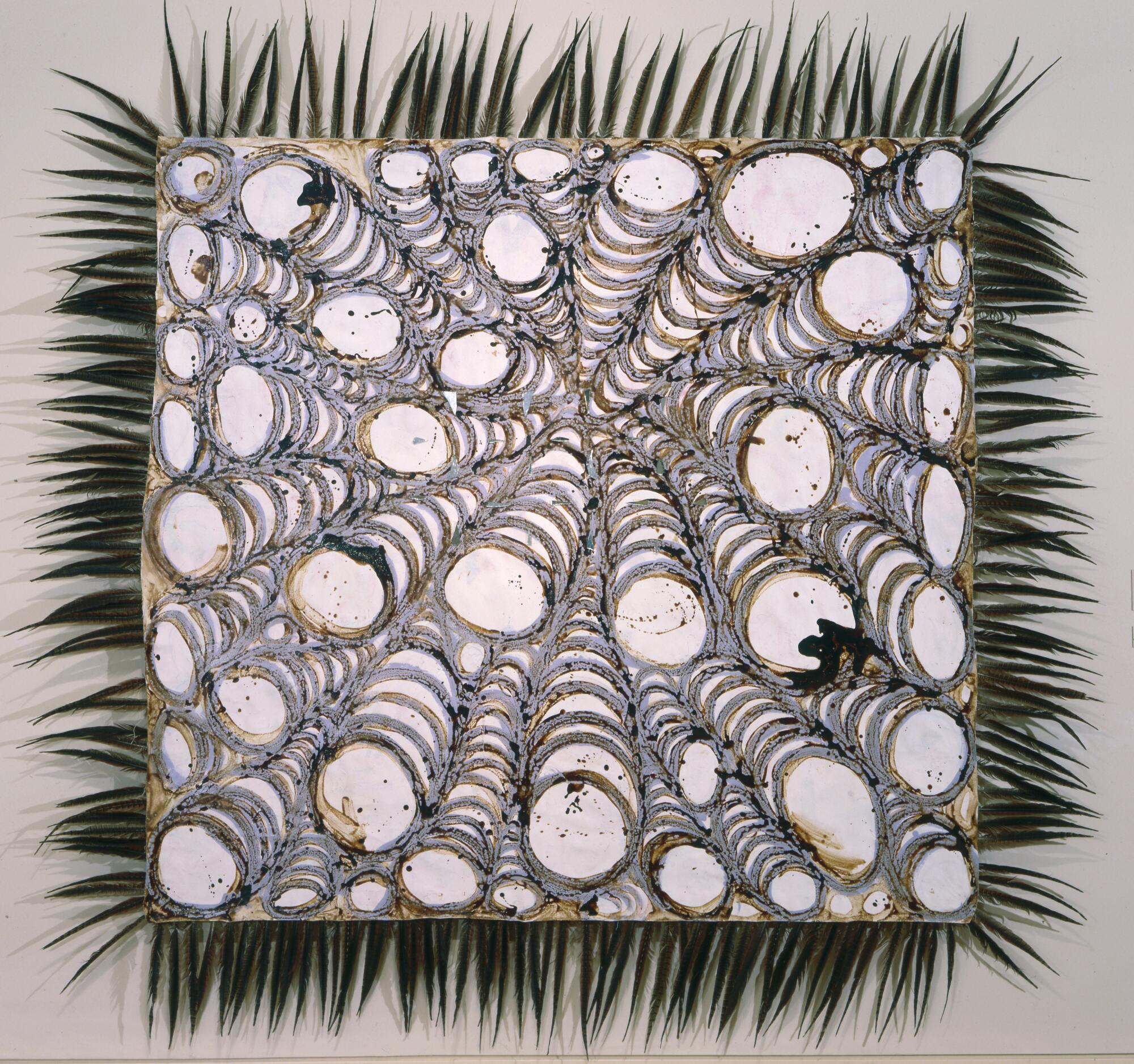 A square canvas by Carls Villa is filled with whorls of circles and is framed in feathers.