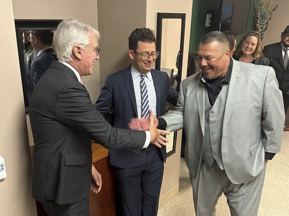 This undated photo, provided the by Los Angeles District Attorney's Office, shows Daniel Saldana, right, shaking hands with Los Angeles District Attorney George Gascon, left. Saldana's lawyer Mike Romano is in the middle. Saldana, who spent 33 years in California prison for attempted murder, has been declared innocent and freed. (Los Angeles County District Attorney's Office via AP)