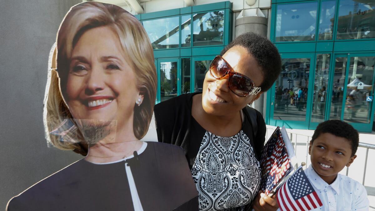 Makia and Emmanuel Nunes pose for a photo with a cutout of Hillary Clinton after several thousands of people were sworn-in as new American citizens at the L.A. Convention Center on Tuesday.
