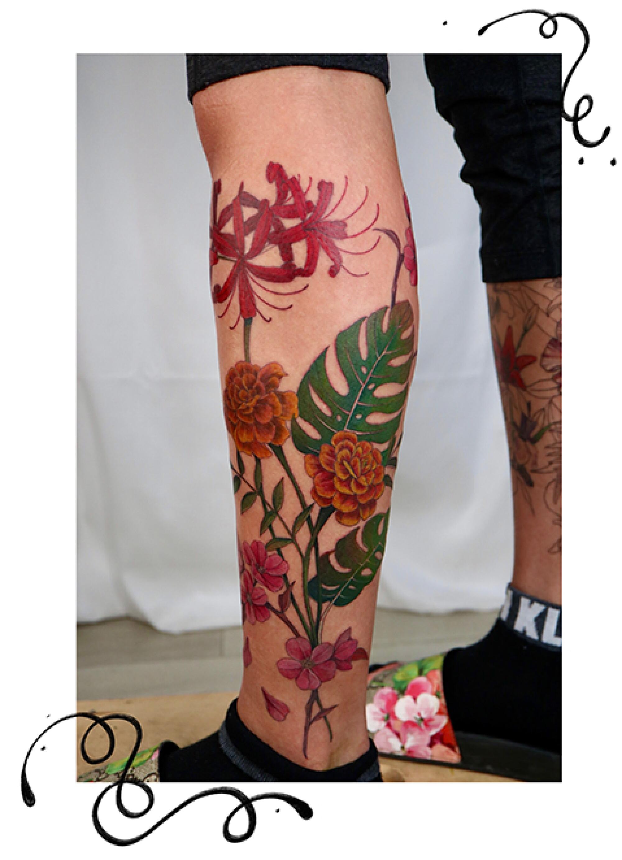 Flowers and plants tattoo on a leg. 