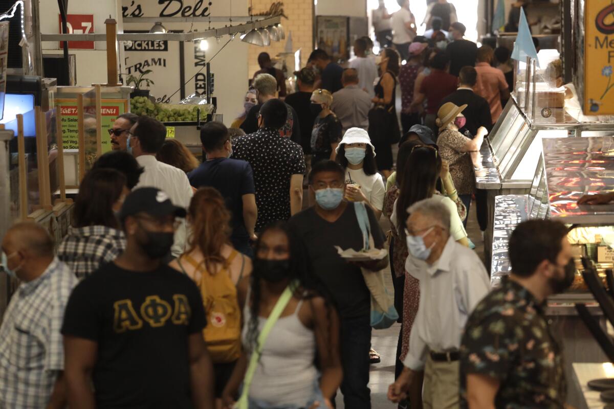 People, many masked, look for lunch at the Grand Central Market.