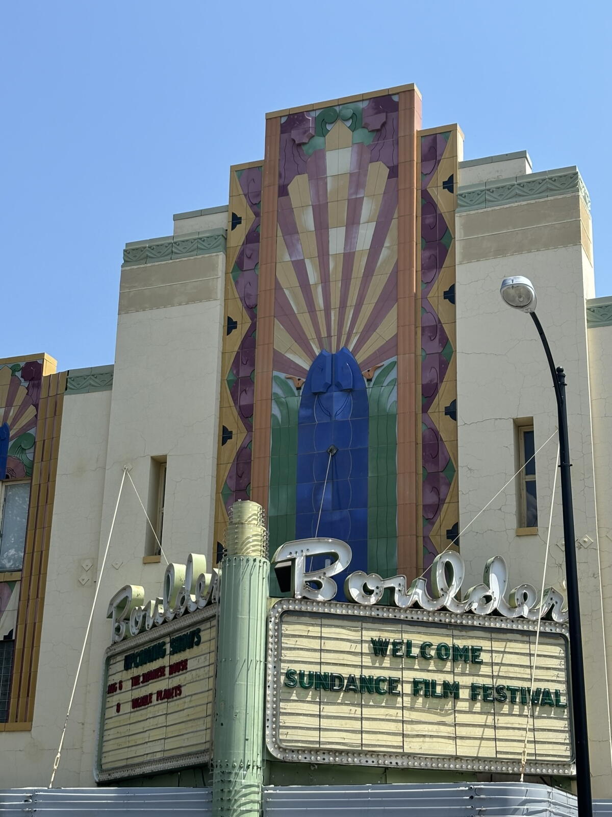 An ornate marquee for a movie theater against a blue sky.