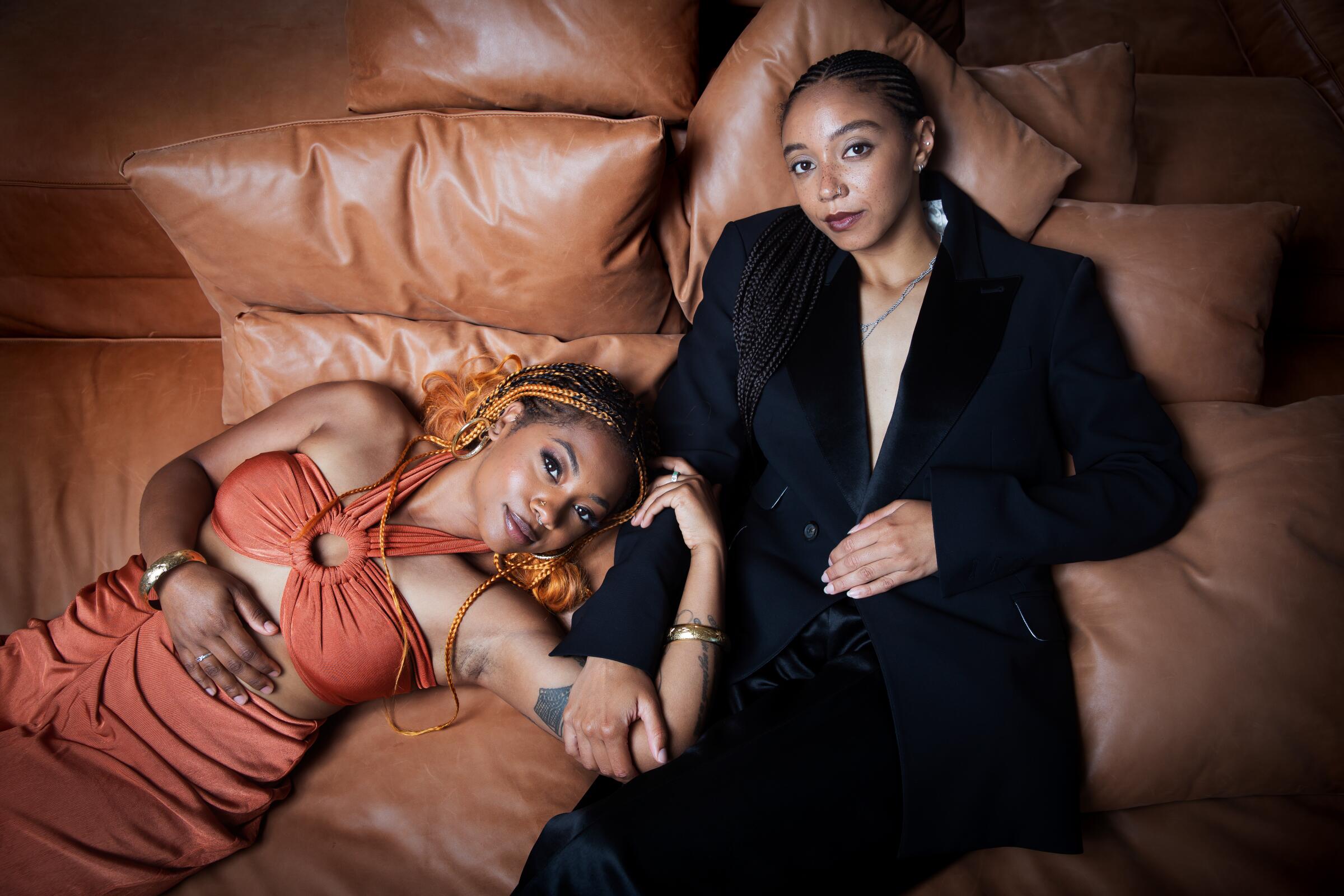 Two women recline on a leather sofa