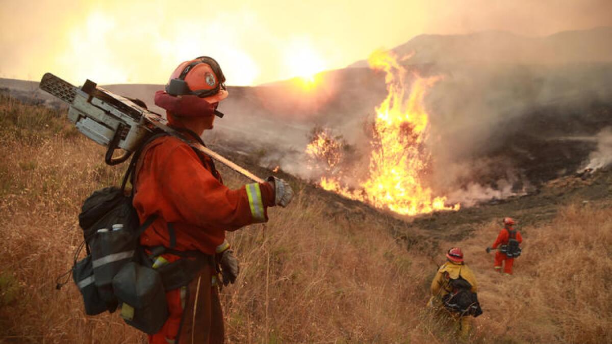 Firefighters in Santa Clarita battle the Sand fire amid sweltering temperatures and heavy winds.