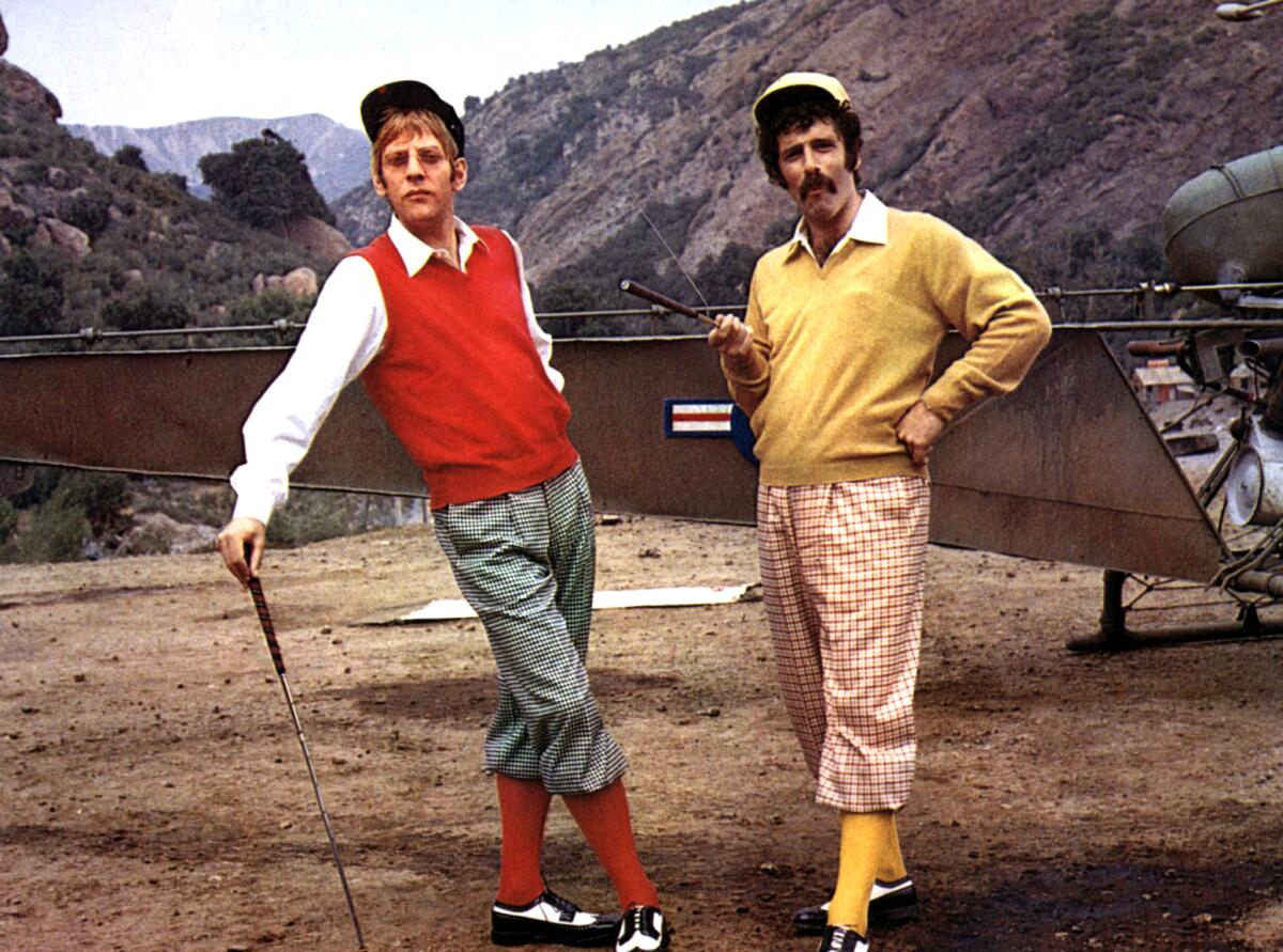 Donald Sutherland and Elliott Gould, wearing golf attire, hold golf clubs in "MASH."