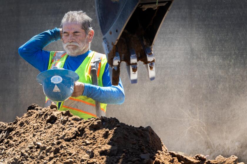 Irvine, CA - September 05: A construction worker takes a quick break to wipe his head while digging a trench with a shovel amidst a heat wave in Irvine Thursday, Sept. 5, 2024. (Allen J. Schaben / Los Angeles Times)