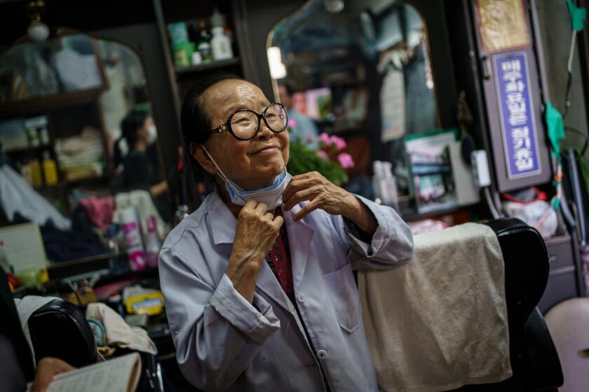 SEOUL, SOUTH KOREA -- THURSDAY, JUNE 4, 2020: Lee Duk-hoon, 84, smiles at a customer at her barbershop called 'Sae Eeyongwon,' which means new barbershop, in Seoul, South Korea, on June 4, 2020. (Marcus Yam / Los Angeles Times)
