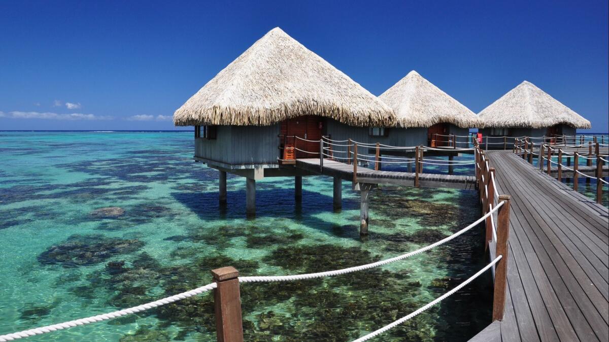 Overwater bungalows show off the waters around Papeete, Tahiti. Round-trip fares are less than $800 for fall through mid-spring.