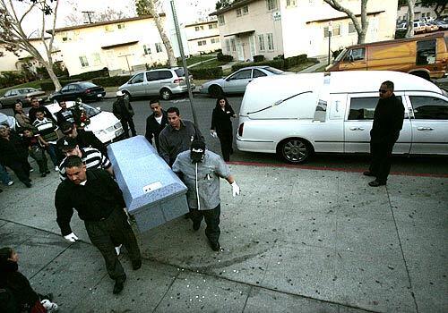 Pallbearers carry the casket of Mauricio Cornejo into St. Teresita Catholic Church in Boyle Heights Wednesday night. Close to two hundred residents of Ramona Gardens (background) attended the funeral. Mauricio died in police custody earlier this month igniting yet another round of police-brutality accusations and countercharges of gang intimidation.