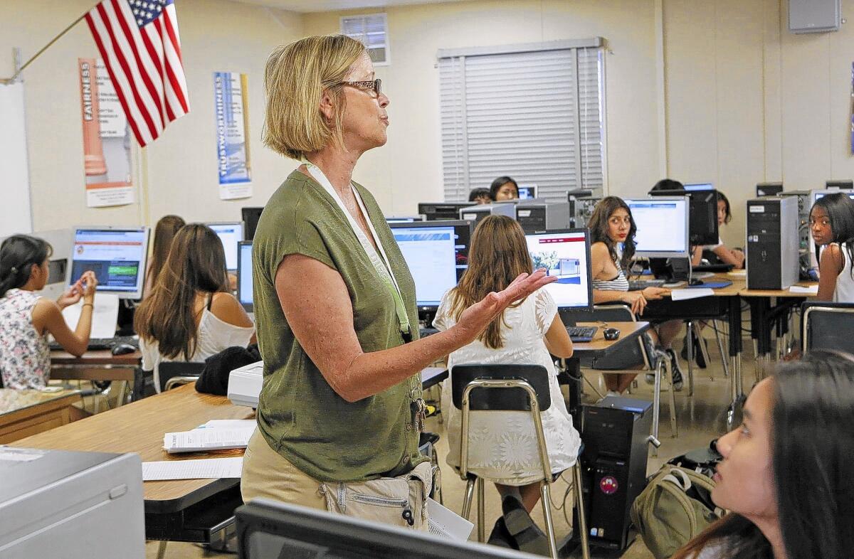 Allison Young, a college counselor at Sherman Oaks Center for Enriched Studies, assists students who are filling out UC applications. UC's online applications were available Aug. 1, months earlier than in previous years.