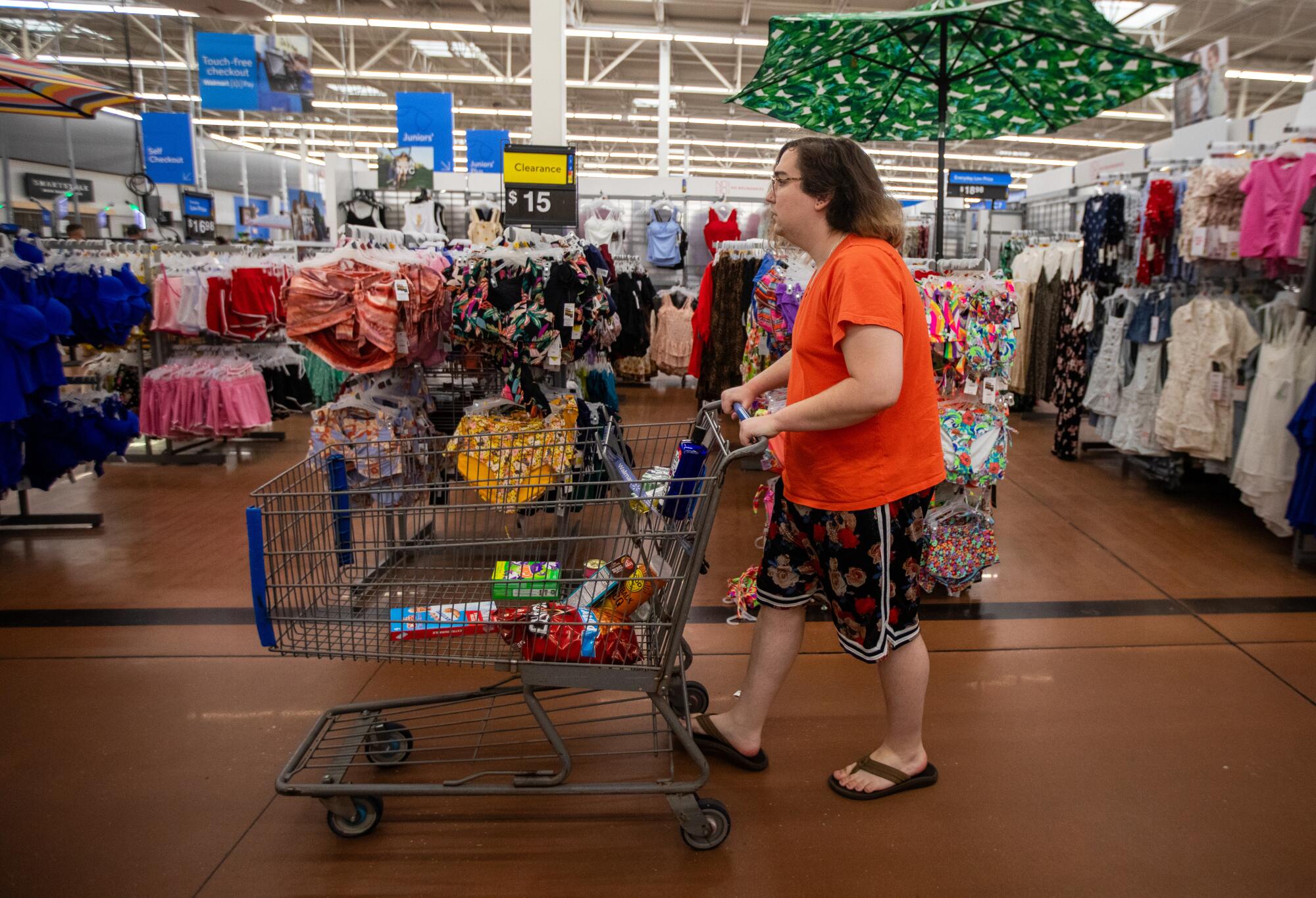A woman pushes a shopping cart through a store.