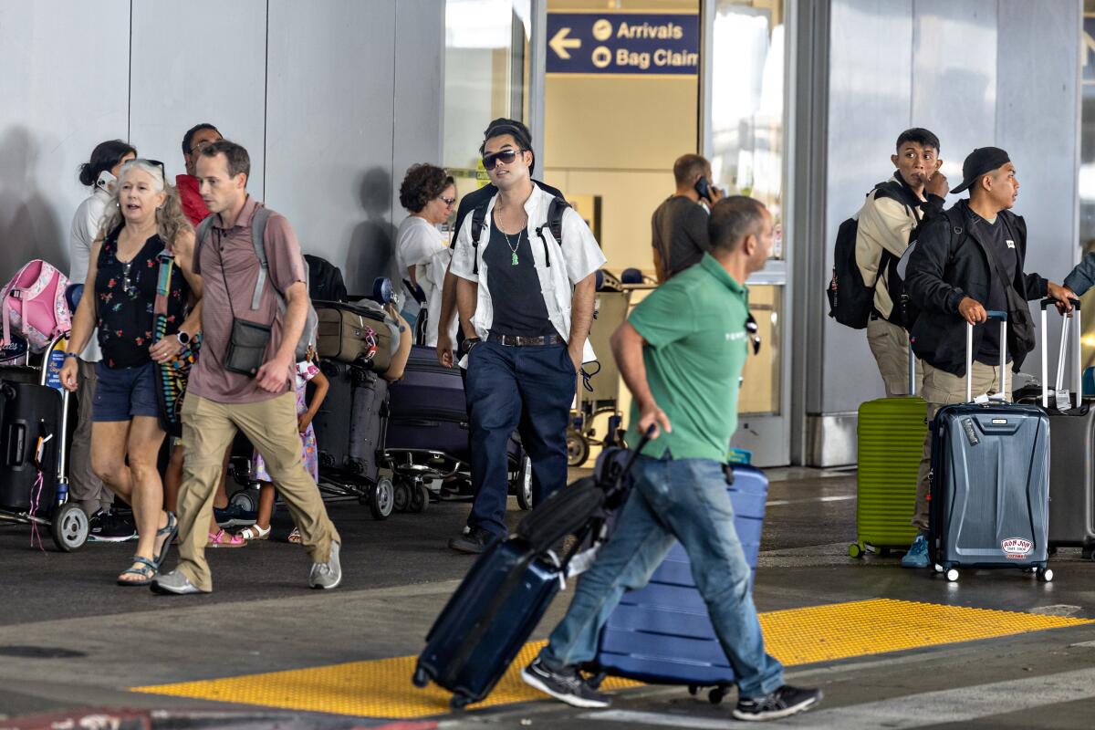 A large number of travelers make their way through Tom Bradley International Terminal at LAX during the busy July 4 holiday.