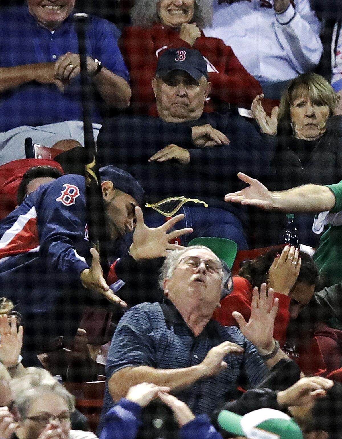 A fan gets hit by the bat after it flew over the protective screening at Fenway Park.