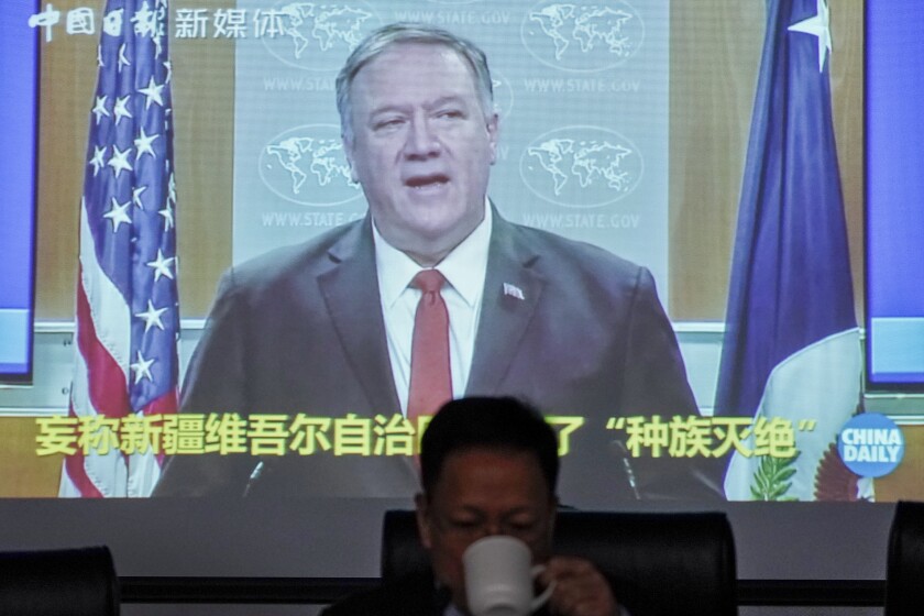 Xu Guixiang, a spokesperson for Xinjiang's Communist Party, drinks as a screen showing a footage of former U.S. Secretary of State Mike Pompeo, during a press conference related to Xinjiang issues at the Ministry of Foreign Affairs office in Beijing, Monday, Feb. 1, 2021. Xu accused Pompeo on Monday of trying to undermine Beijing's relations with President Joe Biden by declaring China's actions against the Uighur ethnic group a "genocide." (AP Photo/Andy Wong)