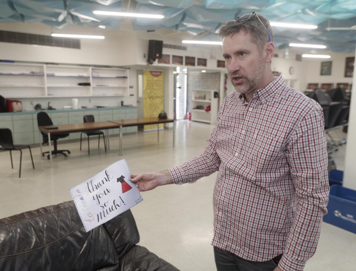 Choir director Dr. Jeffrey Brookey holds a thank-you note from Arroyo Seco Jr. High School, the school that accepted the donation of choir dresses from the La Cañada High School Choral program.