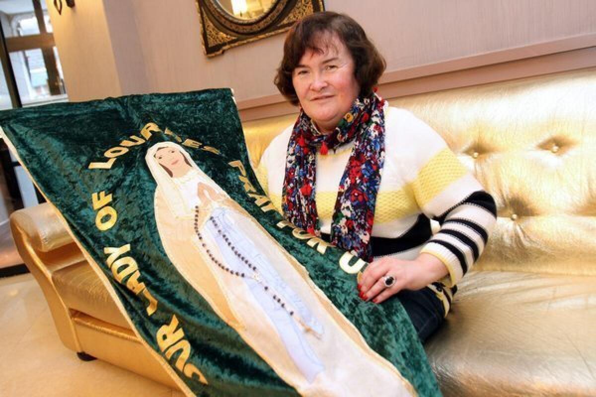 British singer Susan Boyle holds a banner with an image of the Virgin Mary as she poses in a hotel during her pilgrimage to the city of Lourdes, France, back in May.