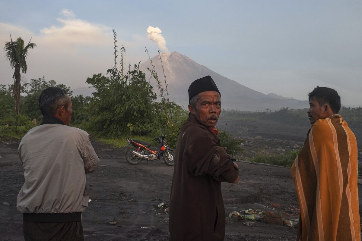 People watch as Mount Semeru spews volcanic materials from it crater in Lumajang, East Java, Indonesia, Monday, Dec. 5, 2022. Improved weather conditions Monday allowed rescuers to resume evacuation efforts and a search for possible victims after the highest volcano on Indonesia's most densely populated island erupted, triggered by monsoon rains. (AP Photo/Dicky Bisinglasi)