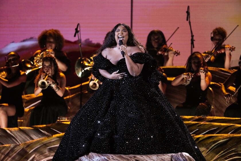 A woman in a black gown singing into a microphone on a stage