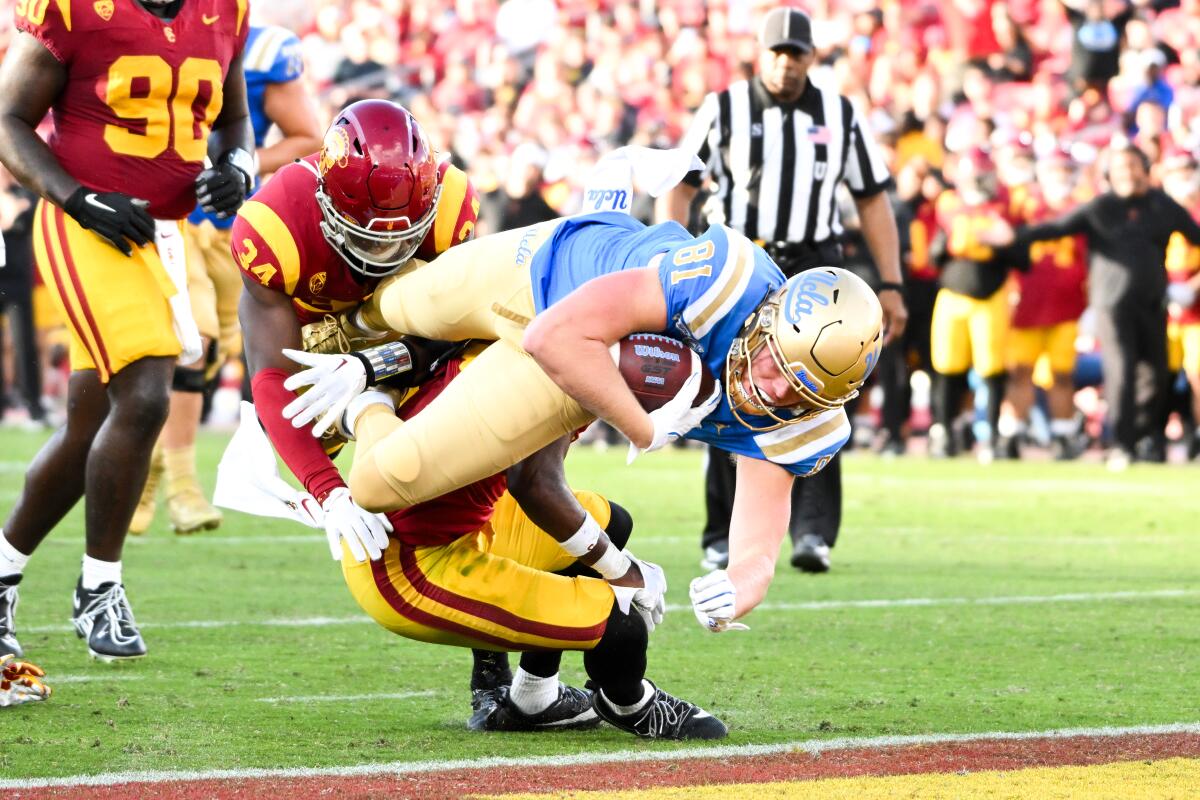 UCLA tight end Hudson Habermehl dives into the end zone past USC safety Anthony Beavers Jr. and defensive end Braylan Shelby.