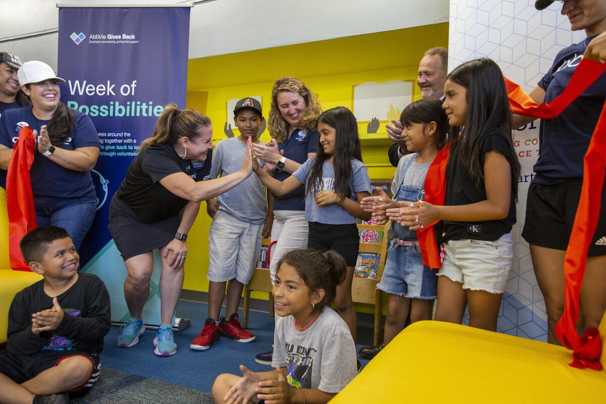  Jill Heath, CEO of Heart of America, high fives Raquel Gutierrez, 9, at Martin Elementary School library. 