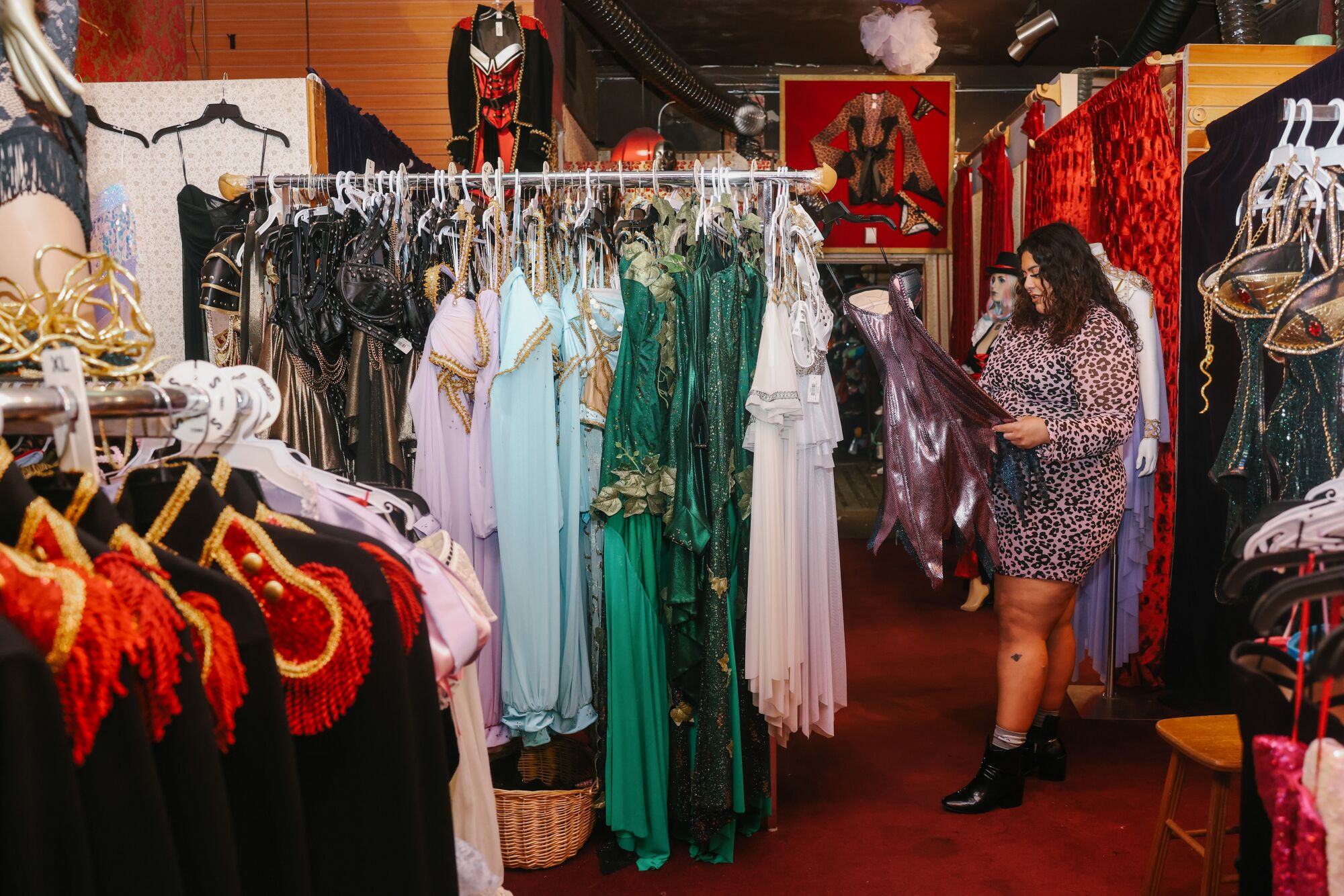 A woman looks at a purple costume dress hanging on a rack at a store.